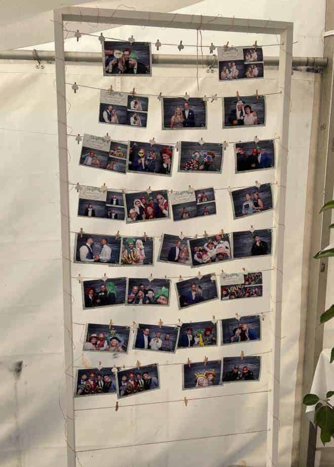 Fotobox-Bilderwand mit gedruckten Hochzeitsfotos an Wäscheleinen mit Mini-Klammern.