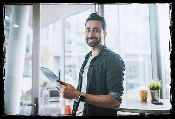 Eine gute Vorbereitung gehört zu jedem gelungenen Event – auch wenn es um die Fotobox geht. Lächelnder Mann mit Klemmbrett – Eventplanung und Organisation im modernen Büro.
