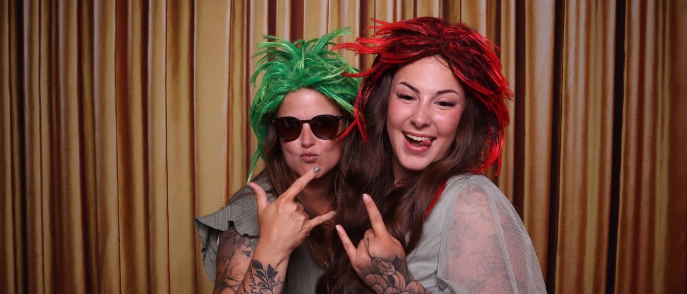 Zwei Frauen mit bunten Perücken und Tattoos posieren ausgelassen – Vorteile Fotobox bei Events kreativ genutzt