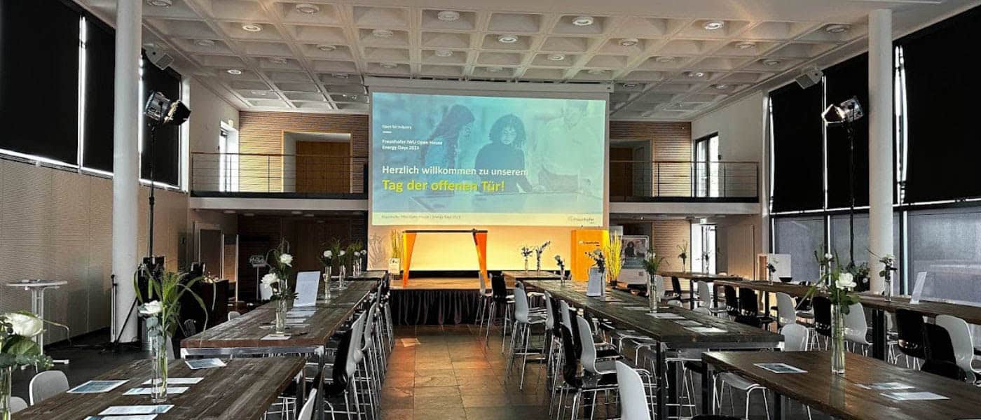 ag der offenen Tür beim Open House / Energy Days am Fraunhofer IWU – stilvoll eingerichteter Veranstaltungsraum mit Bühne und Begrüßungspräsentation.