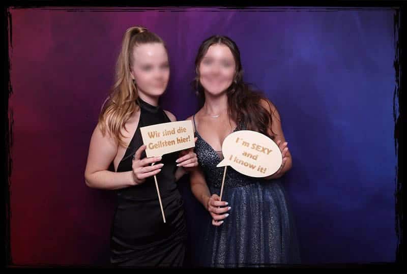 Spaßige Erinnerungen in der Fotobox beim Abiball 2023 Zwei Abiturientinnen posieren mit witzigen Schildern in der Fotobox beim Abiball 2023.