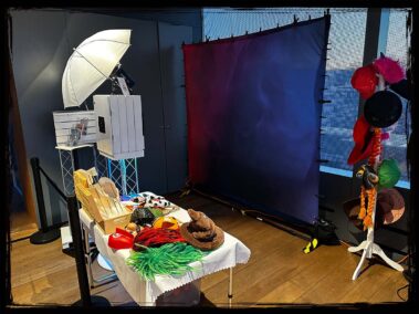 Eine Fotobox auf einem Event mit einer professionellen Beleuchtung und einem schönen Hintergrund. Dazu eine Auswahl an lustigen Accessoires wie Hüte, Perücken und Masken, die den Gästen zur Verfügung stehen. Perfekt für unvergessliche Momente auf Hochzeiten, Geburtstagsfeiern und Firmenevents.