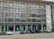Moderne Fassade der IHK Chemnitz mit großen Fenstern, geparkten Autos und Straßenbahnschienen im Vordergrund.