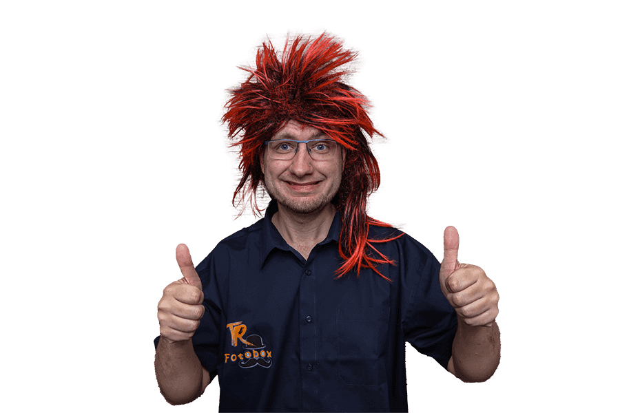 Tommy mit roter Perücke und Daumen hoch, trägt ein TR Fotobox-Shirt – Fotobox mieten Chemnitz für Spaß auf jeder Feier.