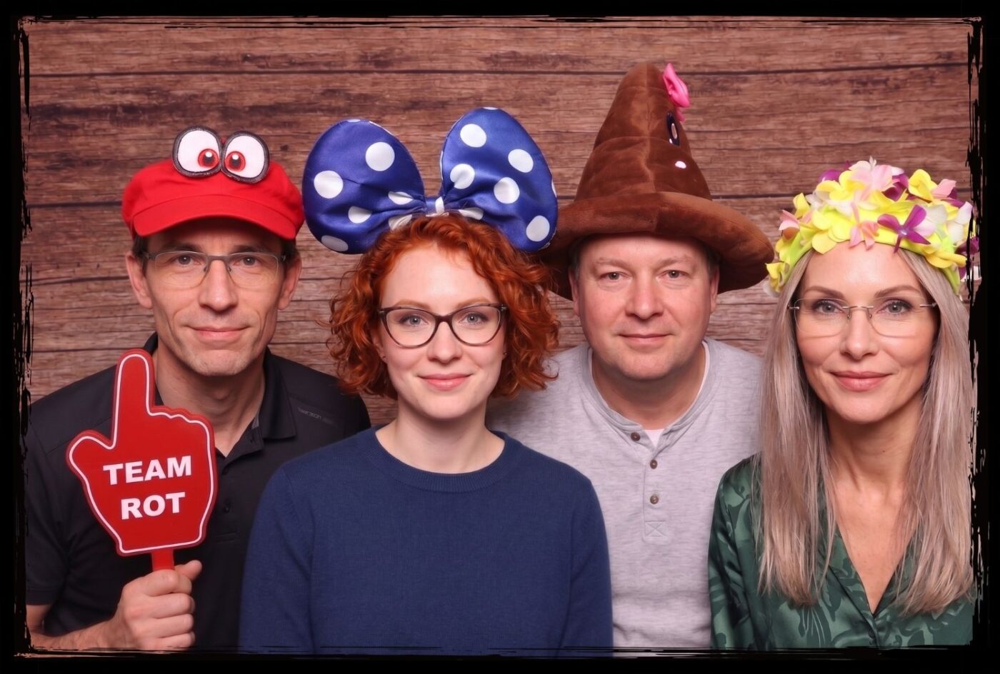 Gruppe mit verschiedenen Fotobox-Hüten und einem Team Rot Hand-Schild