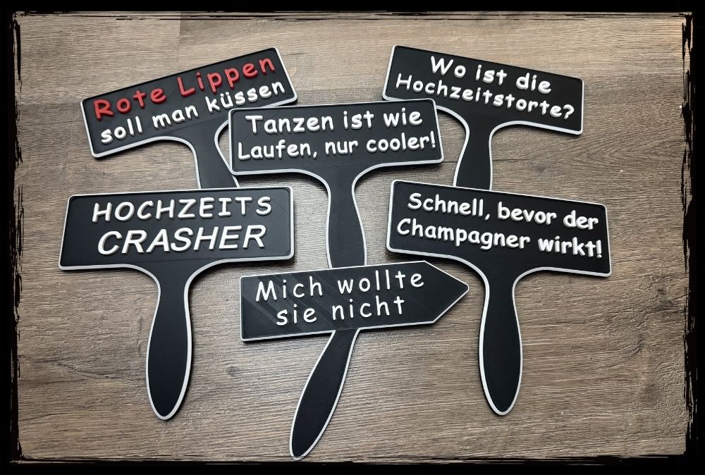 Set aus schwarzen Fotobox-Schildern mit humorvollen Sprüchen zur Hochzeit auf Holzuntergrund.