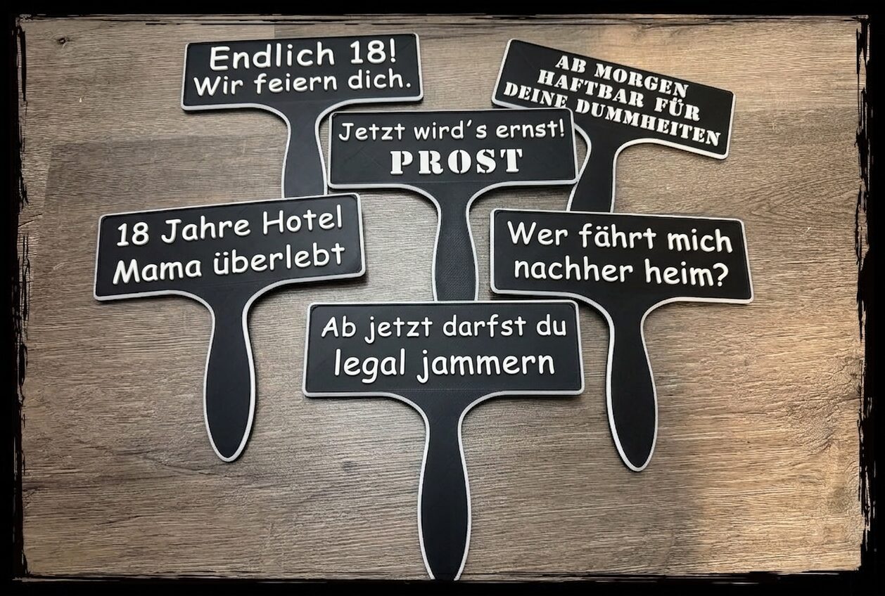 Set aus sechs schwarzen Fotobox Schildern mit lustigen Sprüchen für den 18. Geburtstag auf einem Tisch mit Konfetti