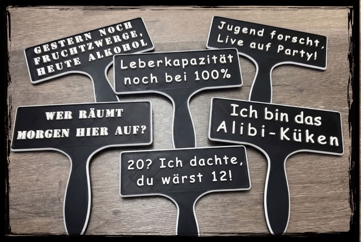 Sechs schwarze Fotobox Schilder für den Geburtstag mit weisser Schrift und frechen Partysprüchen auf einem Holzboden