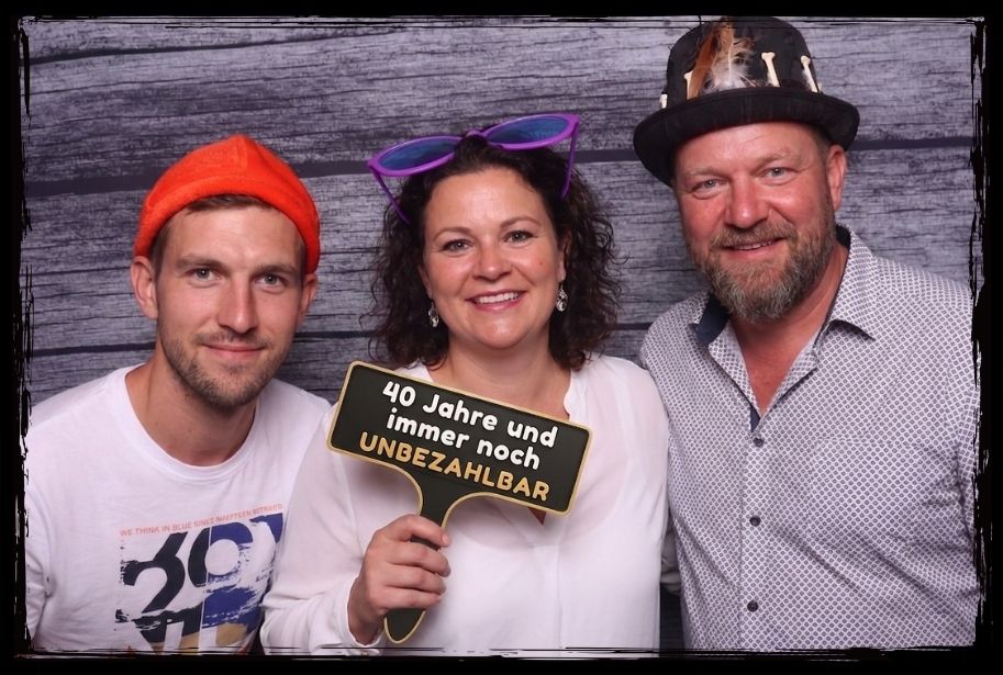 Gäste posieren mit Party-Accessoires und einem Fotobox Schild für den 40er